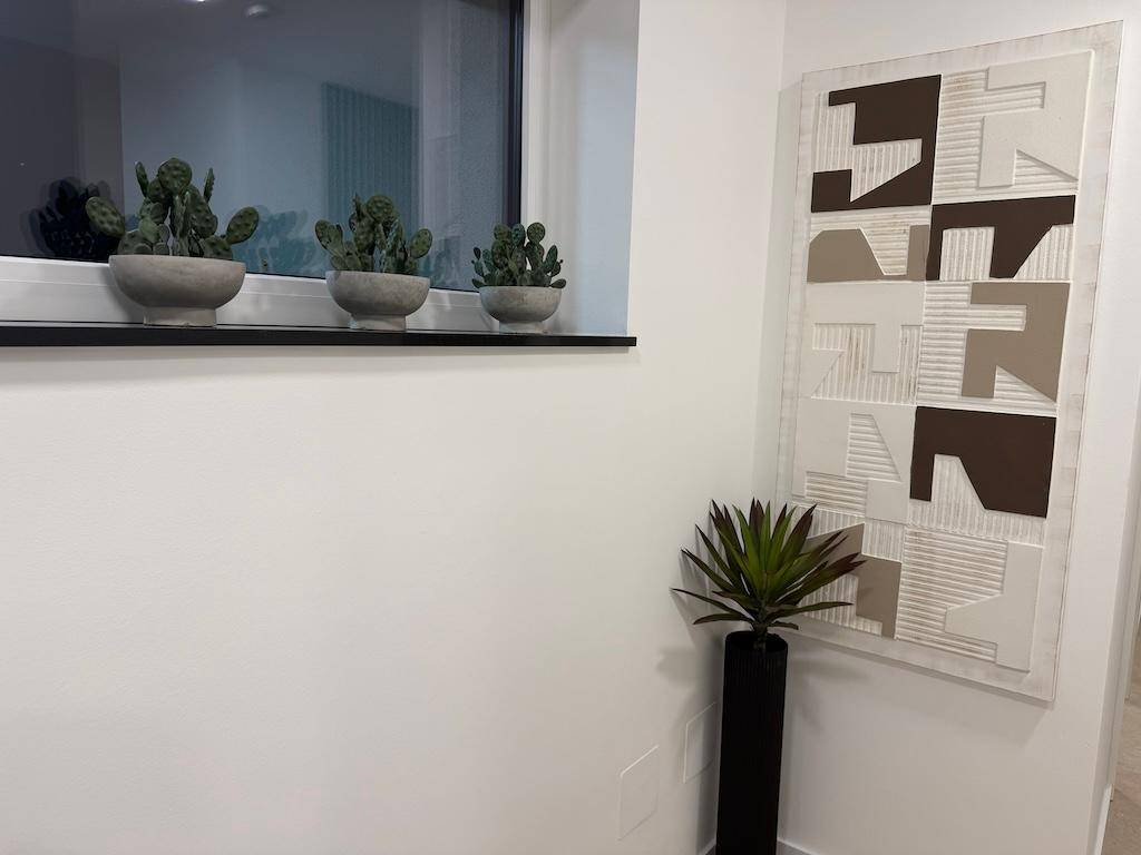 Detailansicht eines Fenstersims mit Kakteen und einem modernen, geometrischen Wandbild.