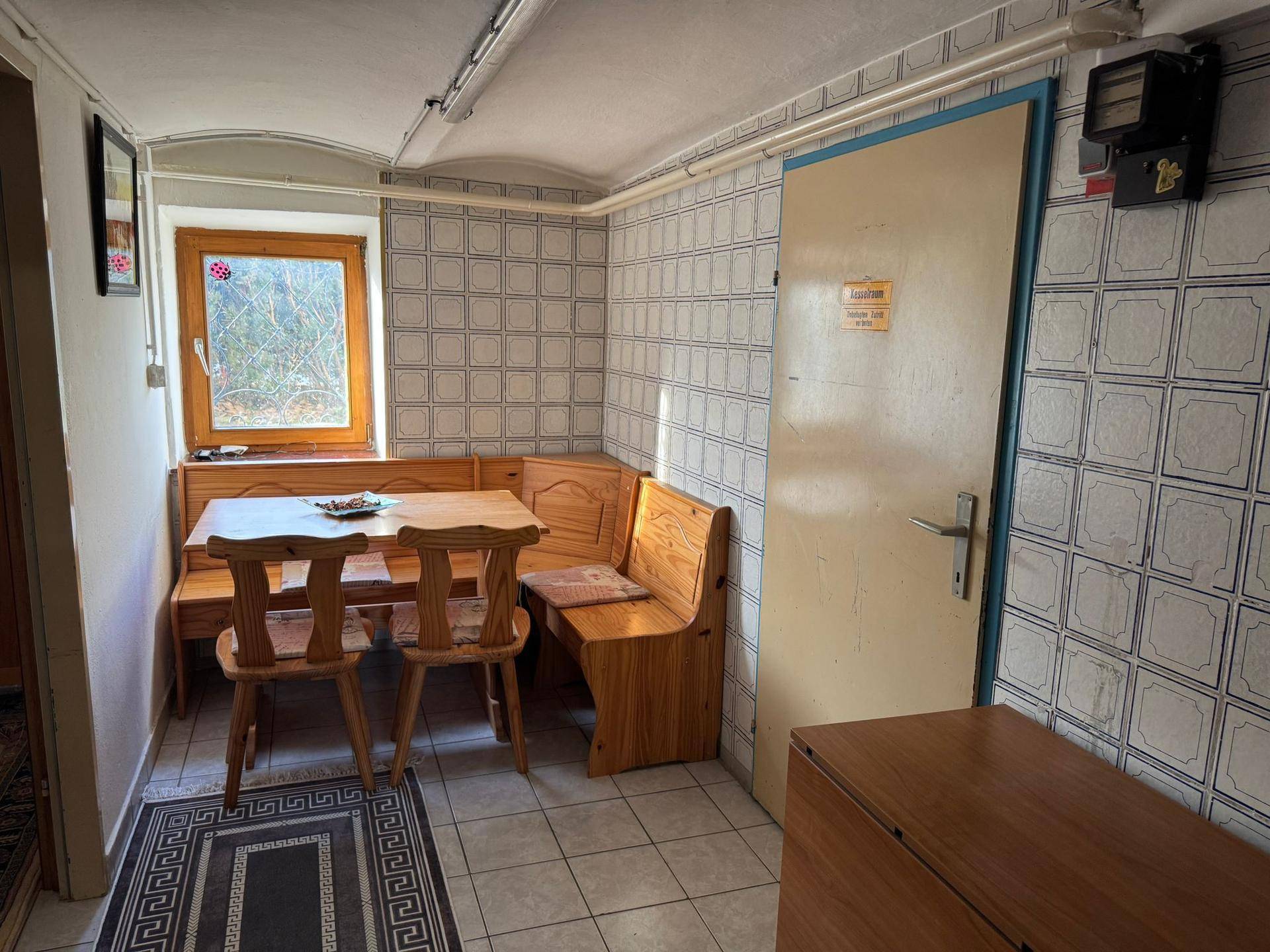 Kellerraum mit rustikaler Sitzecke, Holztisch und gefliesten Wänden.
