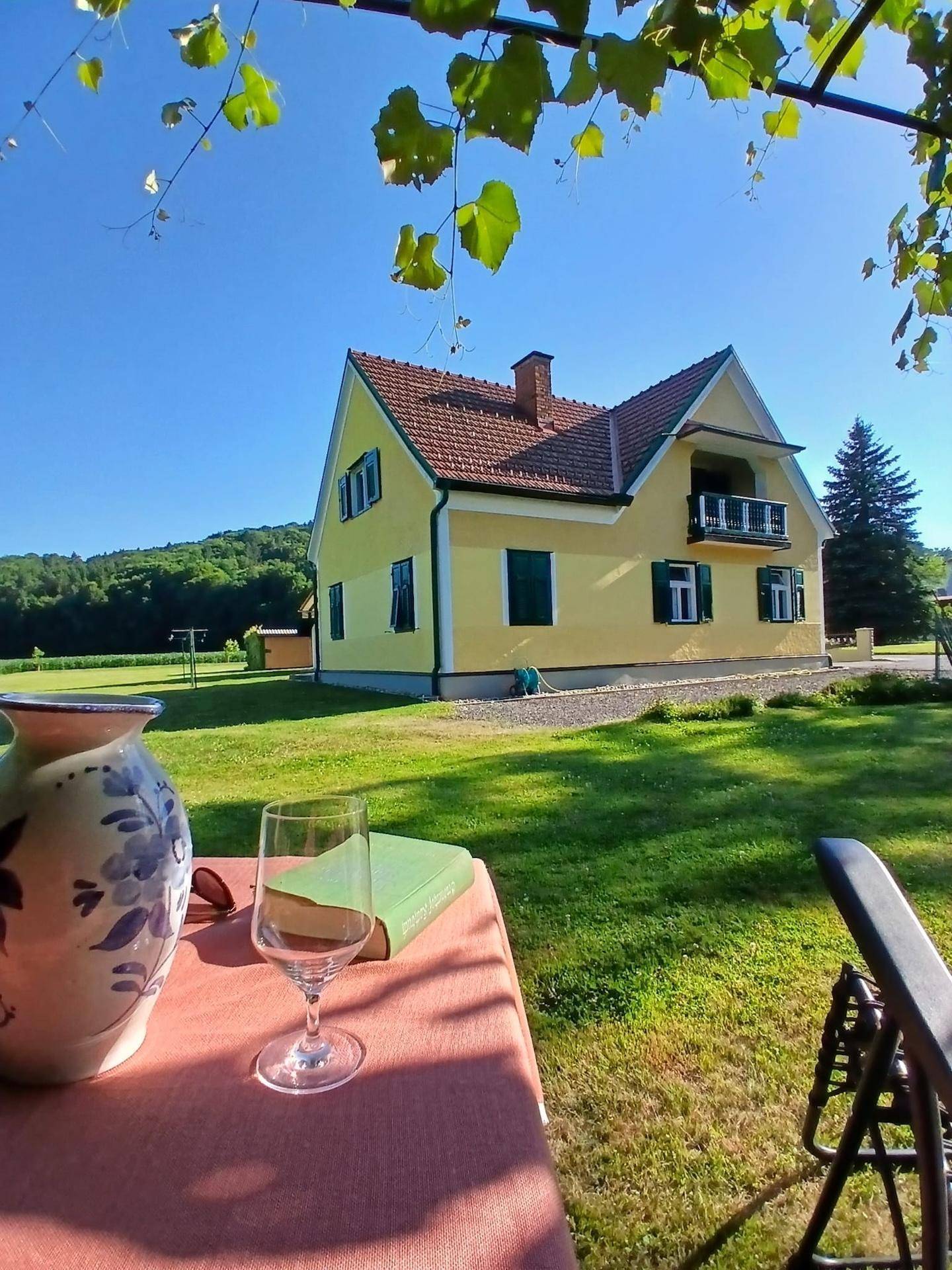Charmantes gelbes Landhaus mit rotem Ziegeldach, umgeben von einem weitläufigen grünen Garten.