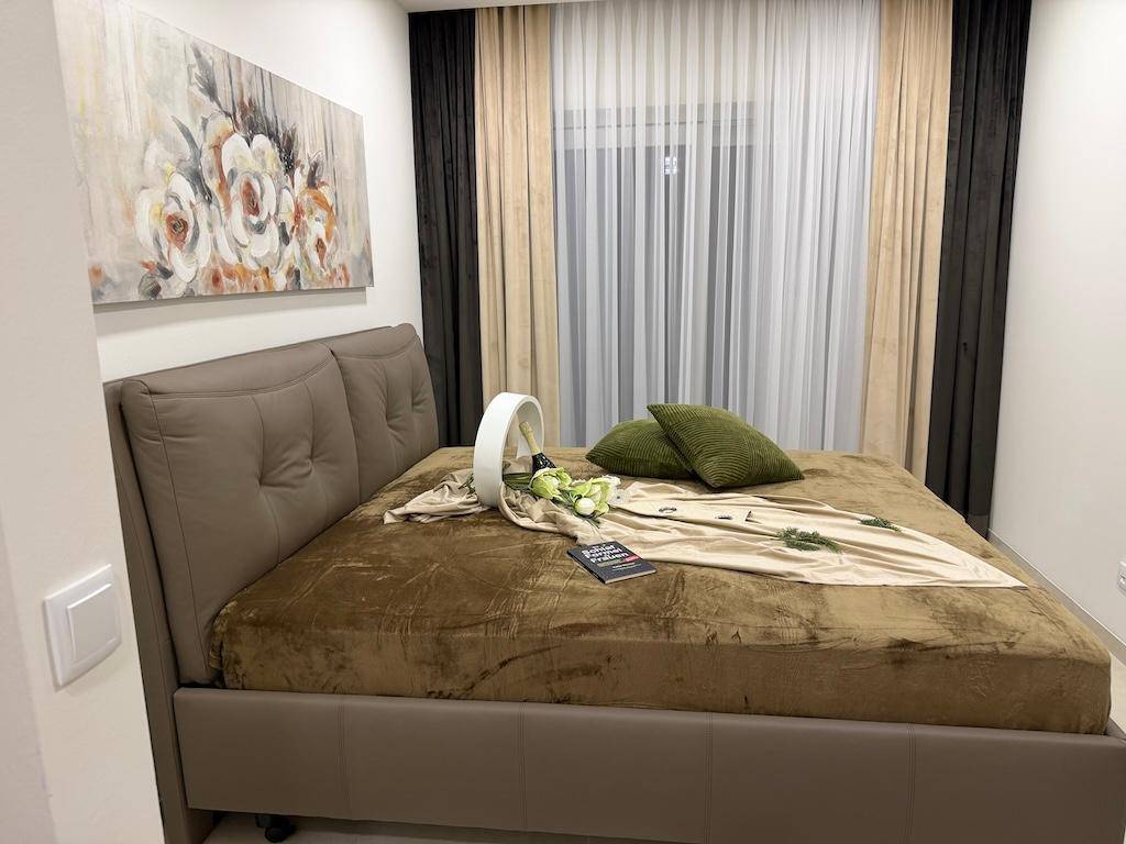 Gemütliches Schlafzimmer mit großem Doppelbett, Kunstwerk und Vorhängen am Fenster.