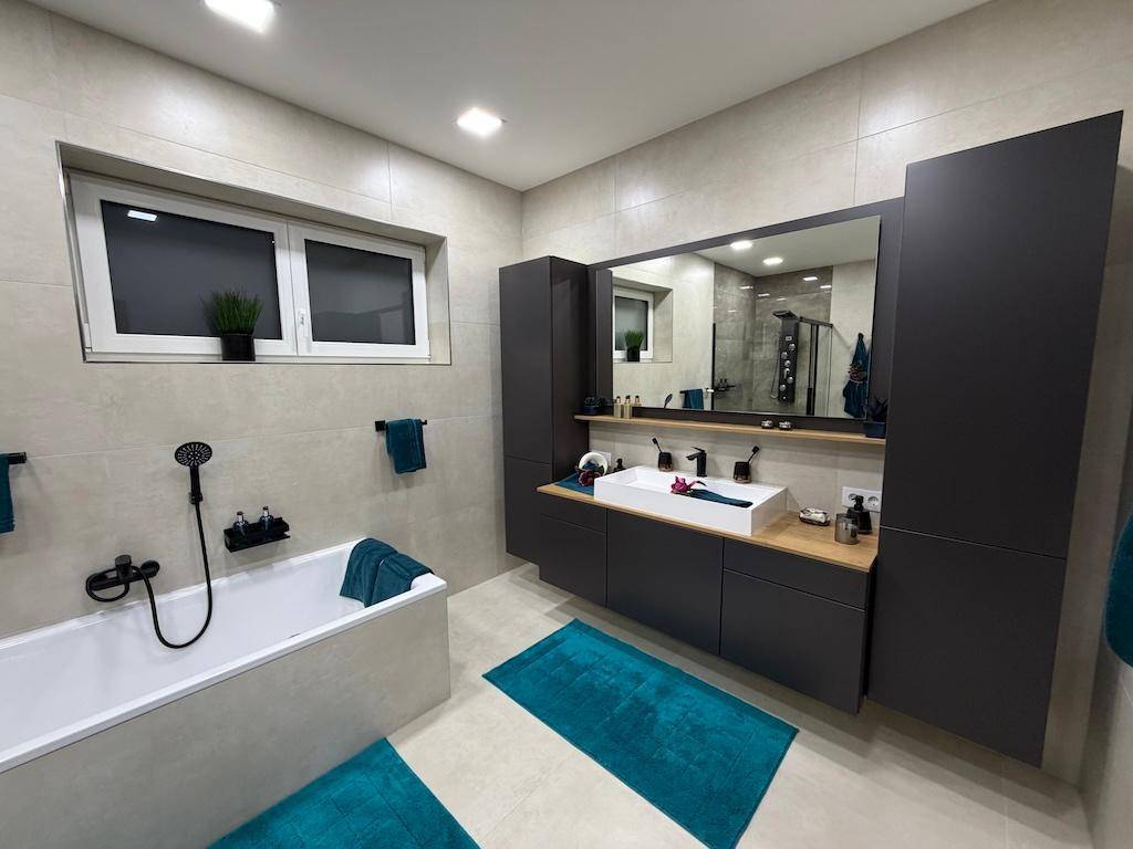 Elegantes Badezimmer mit großem Doppelwaschbecken, Badewanne und modernen dunklen Schränken.
