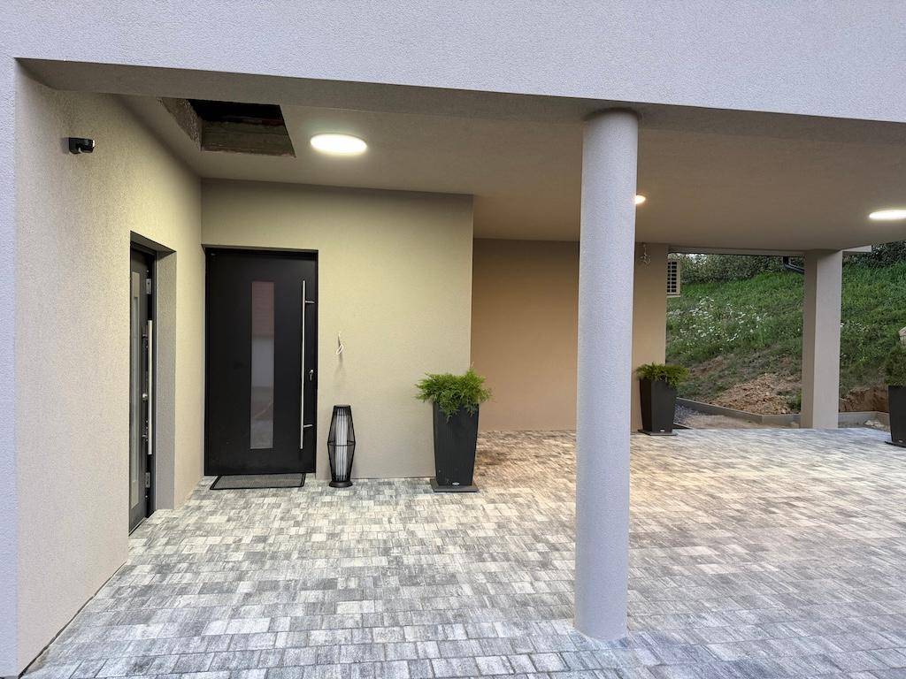 Geräumiger überdachter Eingangsbereich mit Säule und Zugang zum Carport.