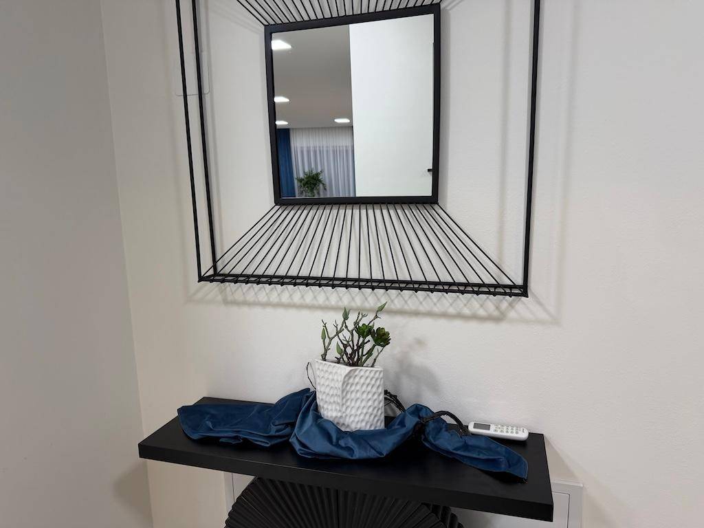 Detailaufnahme eines modernen Spiegels mit schwarzem Rahmen über einer Konsole mit Dekoration.