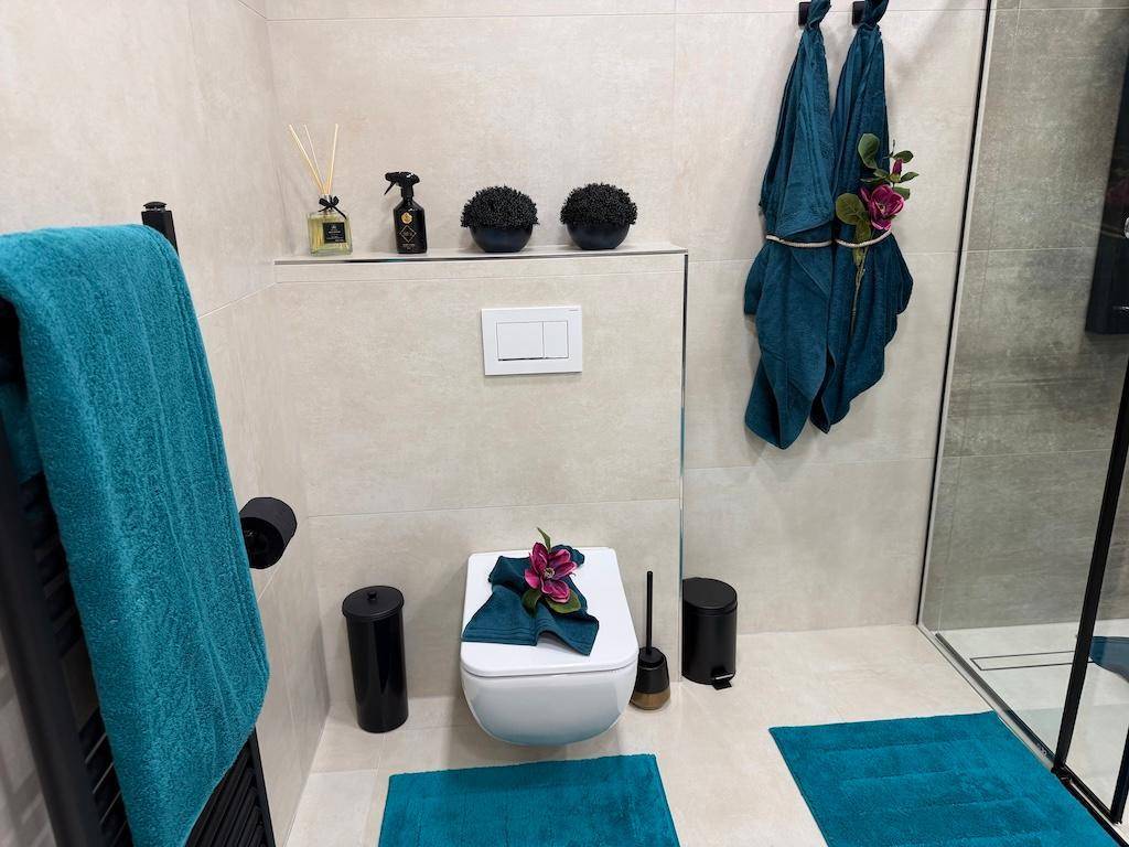 Modernes Badezimmer mit wandhängendem WC, Duschbereich und beheiztem Handtuchhalter.