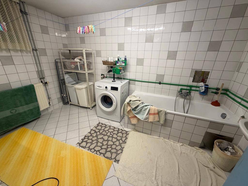 Kellerraum als Waschküche mit Waschmaschine, Badewanne und Wäscheleine.