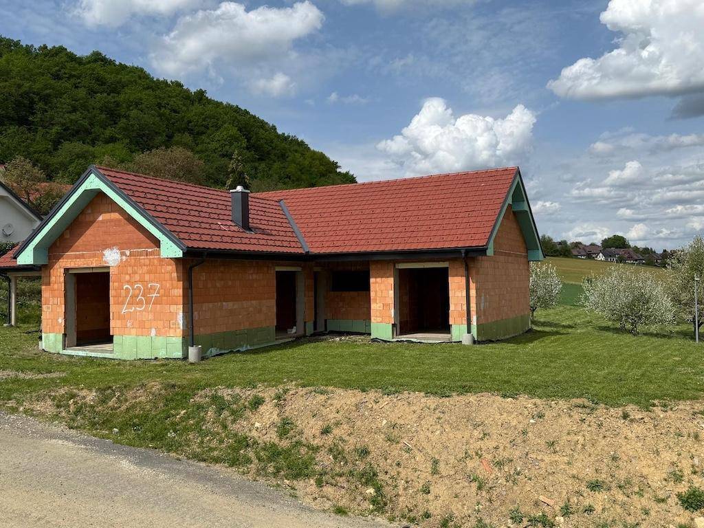 Neubau eines Einfamilienhauses im Rohbau mit rotem Ziegeldach und der Nummer 237 an der Wand.