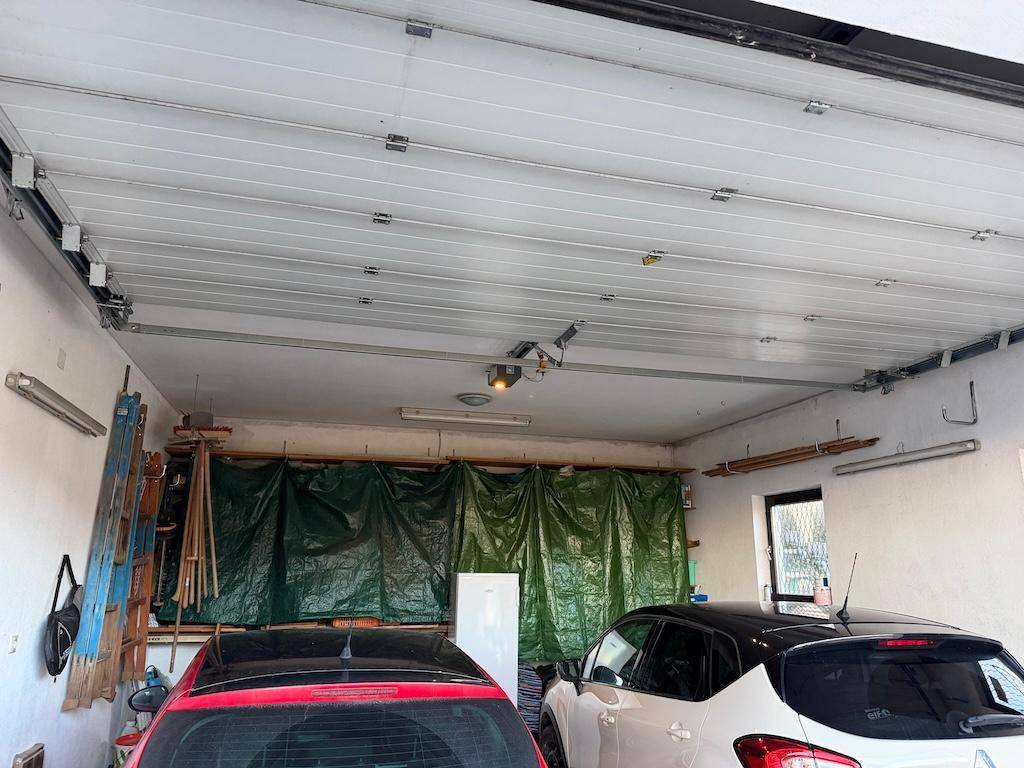 Geräumige Garage mit zwei geparkten Autos, Werkzeugen und Stauraum.