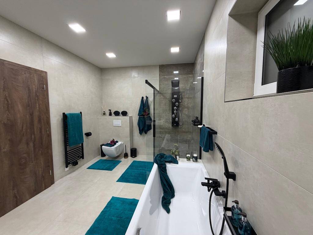 Modernes Badezimmer mit Badewanne, Duschkabine, WC und beheiztem Handtuchhalter.