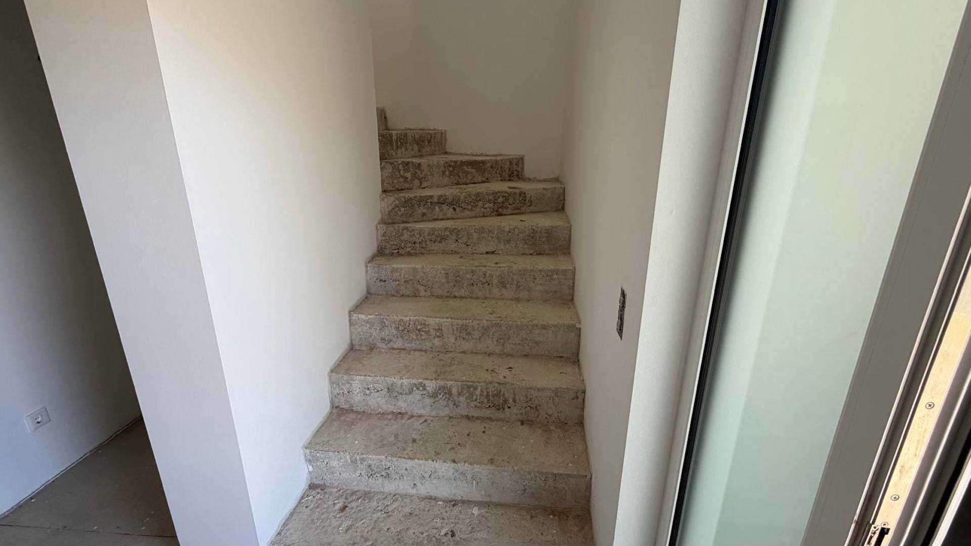 Unfertige Betontreppe in einem Rohbau, die in ein oberes Stockwerk führt und auf den Ausbau wartet.