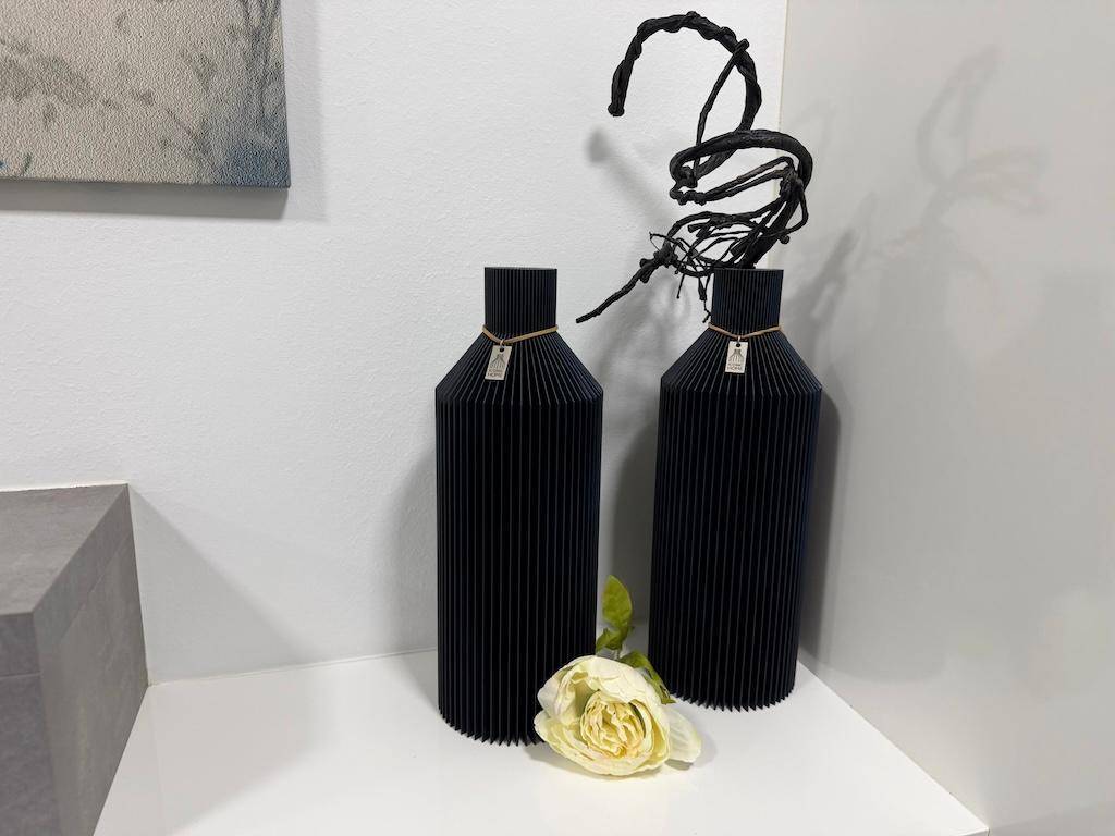 Detailaufnahme von zwei schwarzen Vasen und einer weißen Rose als stilvolle Dekoration.