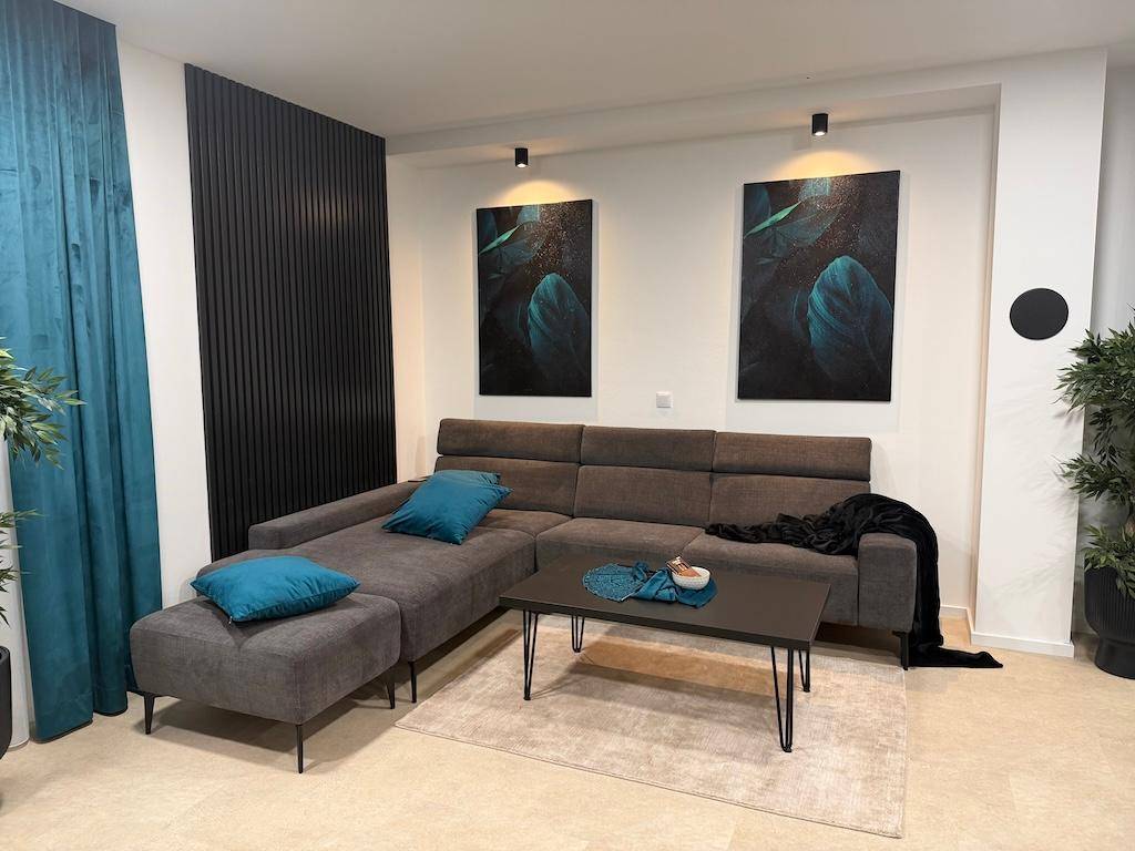 Modernes Wohnzimmer mit einem großen Ecksofa, Couchtisch und dekorativen Wandbildern.