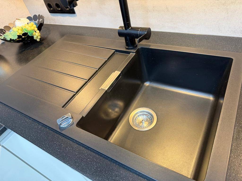 Detailaufnahme einer modernen schwarzen Küchenspüle mit passender schwarzer Armatur.