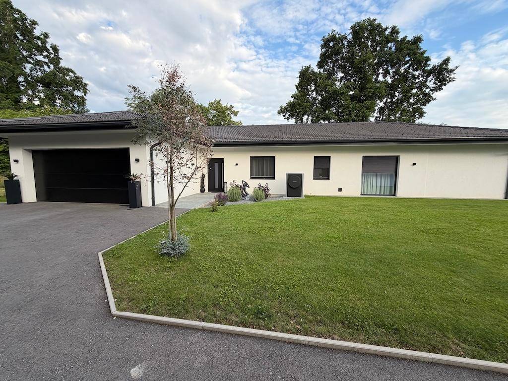 Vorderansicht des modernen Einfamilienhauses mit Garage, gepflegtem Vorgarten und breiter Zufahrt.