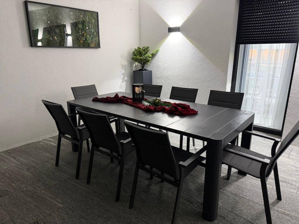 Überdachter Essbereich auf der Terrasse mit großem Tisch und Stühlen, ideal für gesellige Abende.