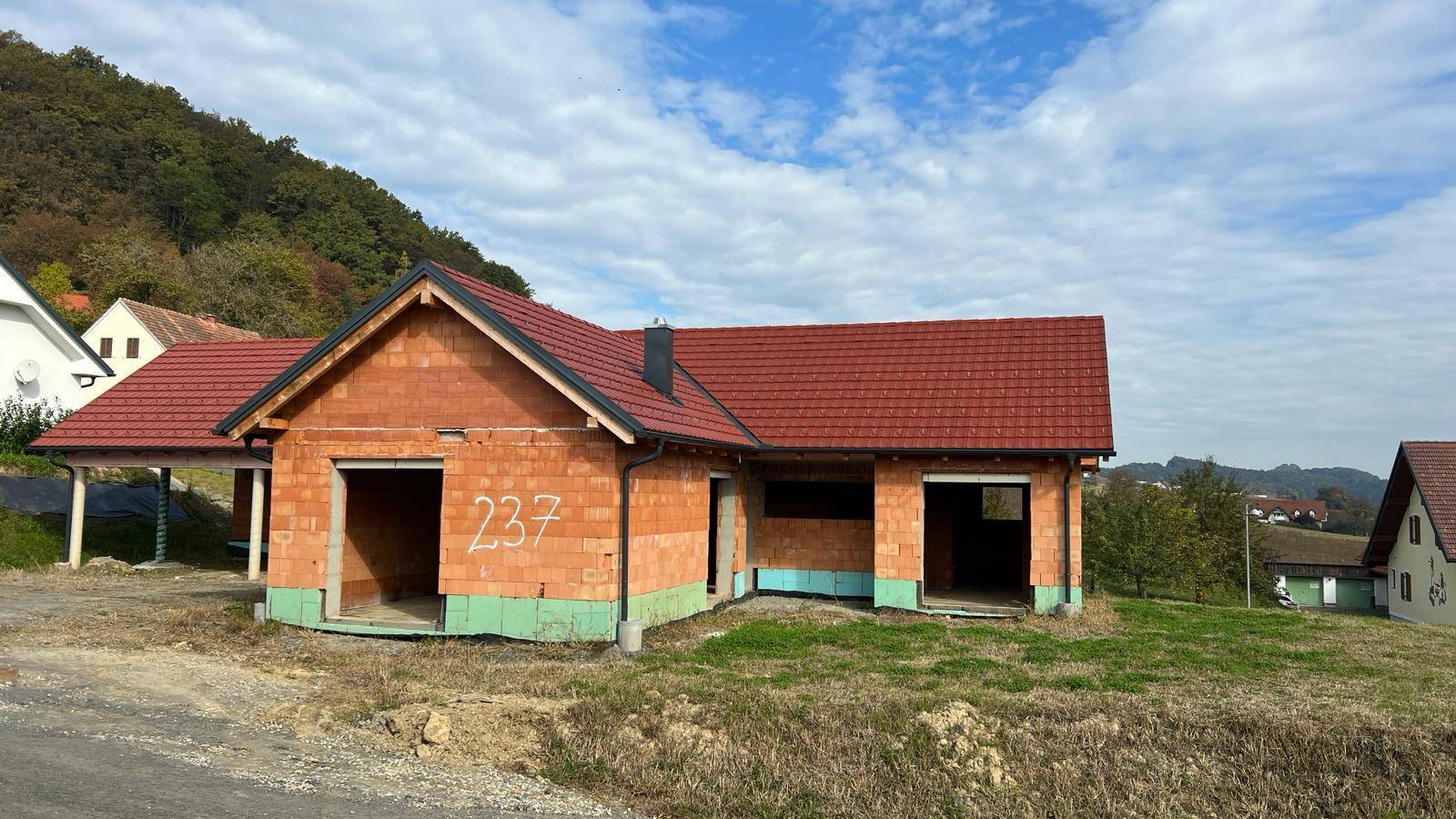 Rohbau eines Einfamilienhauses mit rotem Ziegeldach und der Nummer 237 an der Fassade.