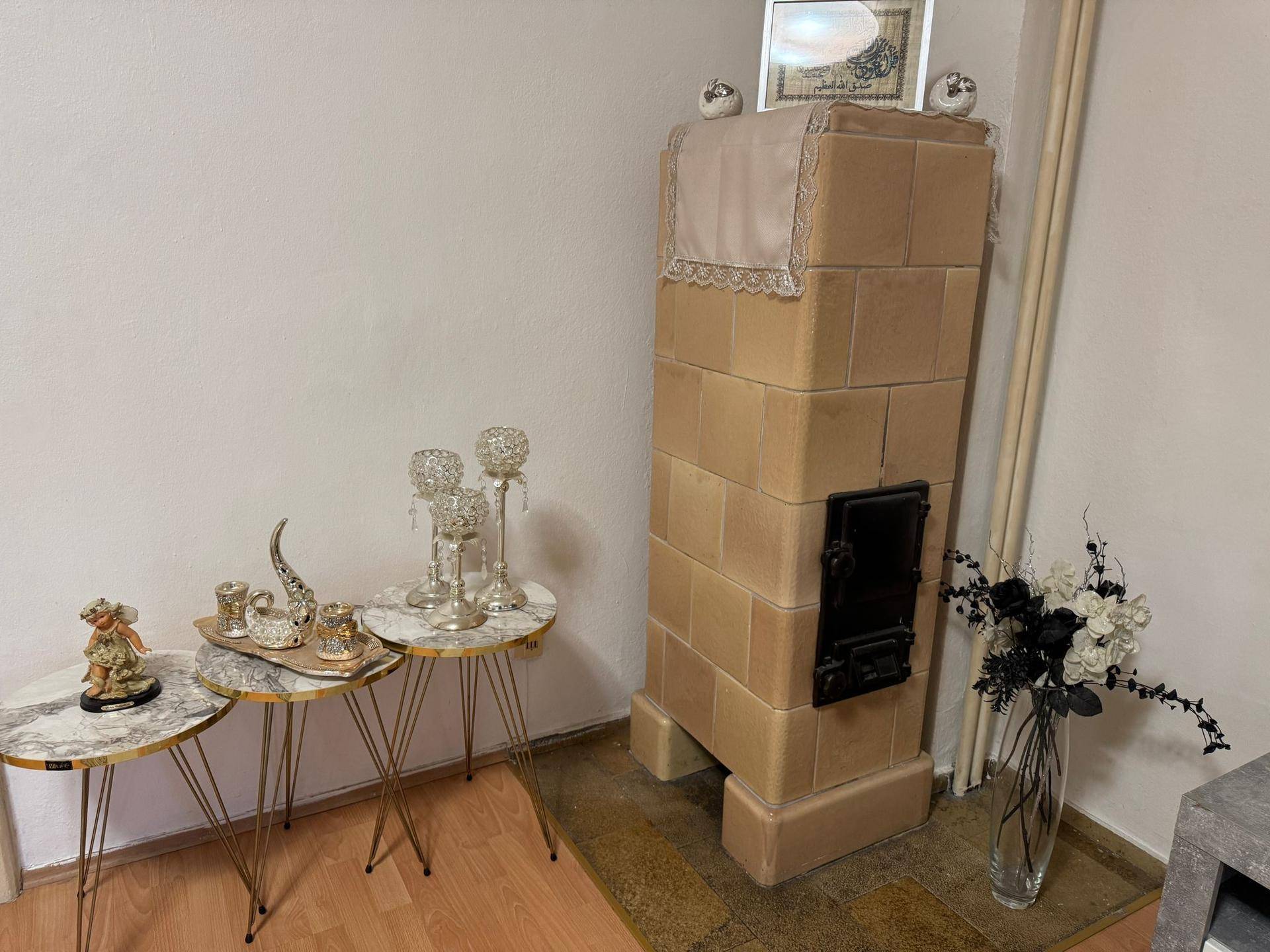 Detailansicht eines traditionellen Kachelofens im Wohnzimmer mit dekorativen Beistelltischen.