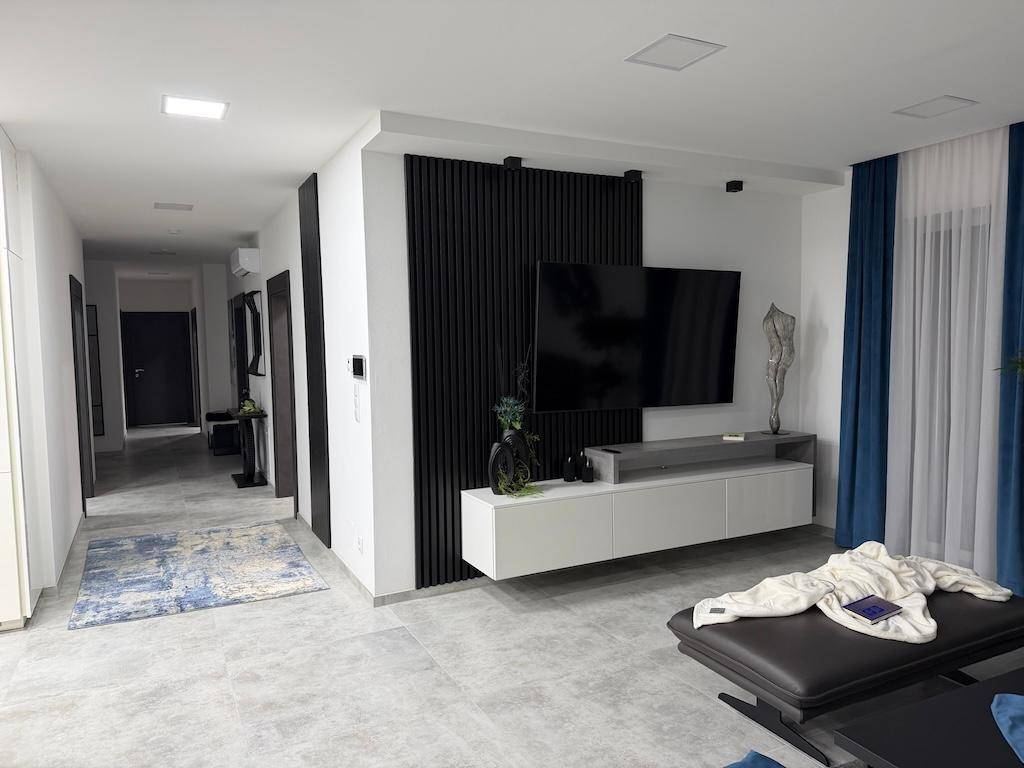 Blick vom Wohnzimmer in einen modernen Flur mit Fliesenboden und minimalistischer Einrichtung.