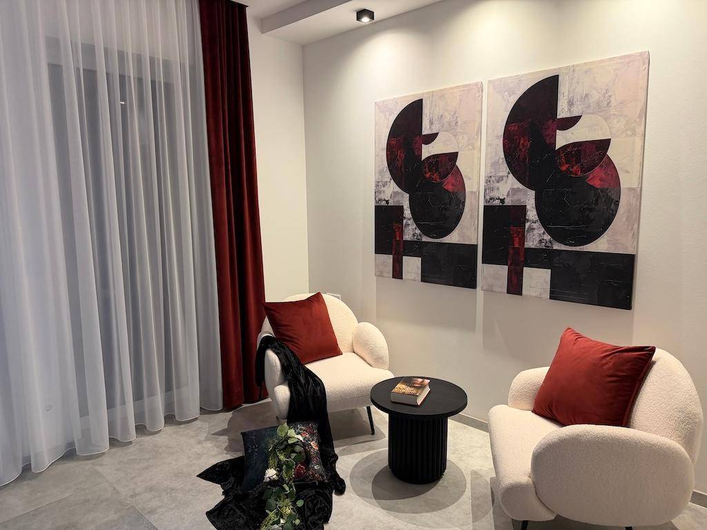 Elegante Sitzecke mit weichen Sesseln, einem kleinen Tisch und abstrakten Bildern an der Wand.
