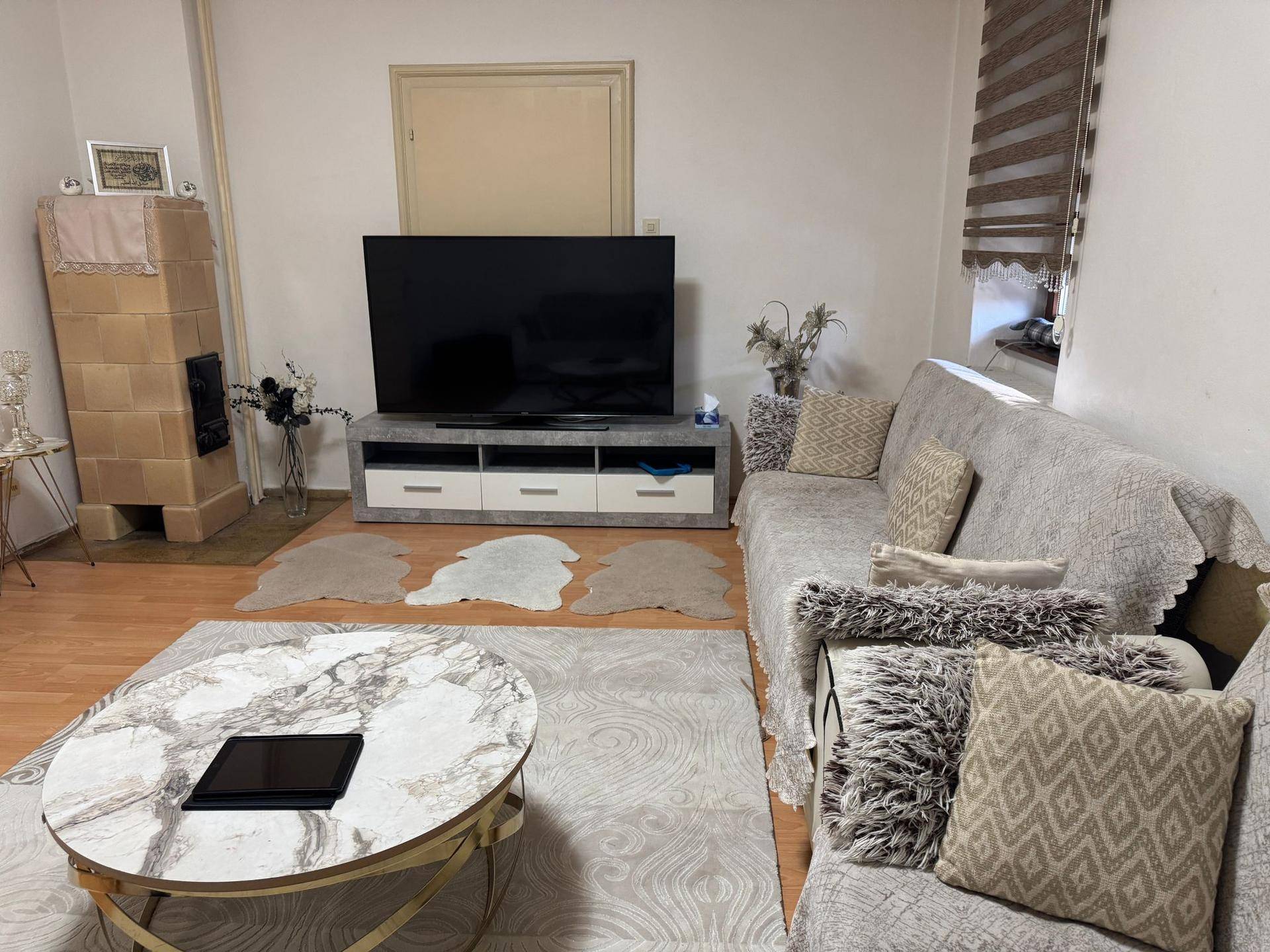 Wohnzimmer mit traditionellem Kachelofen, großem Fernseher und bequemen Sofas.
