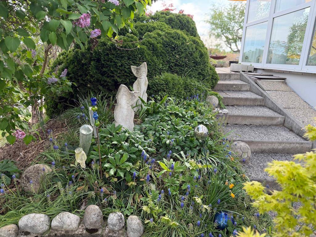 Gepflegter Gartenbereich mit Stufen, Pflanzen und dekorativen Statuen, inklusive einer Rampe.