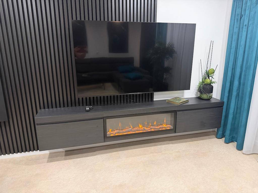 Moderner Wohnbereich mit großem Fernseher, schwebendem TV-Möbel und integriertem Elektrokamin.