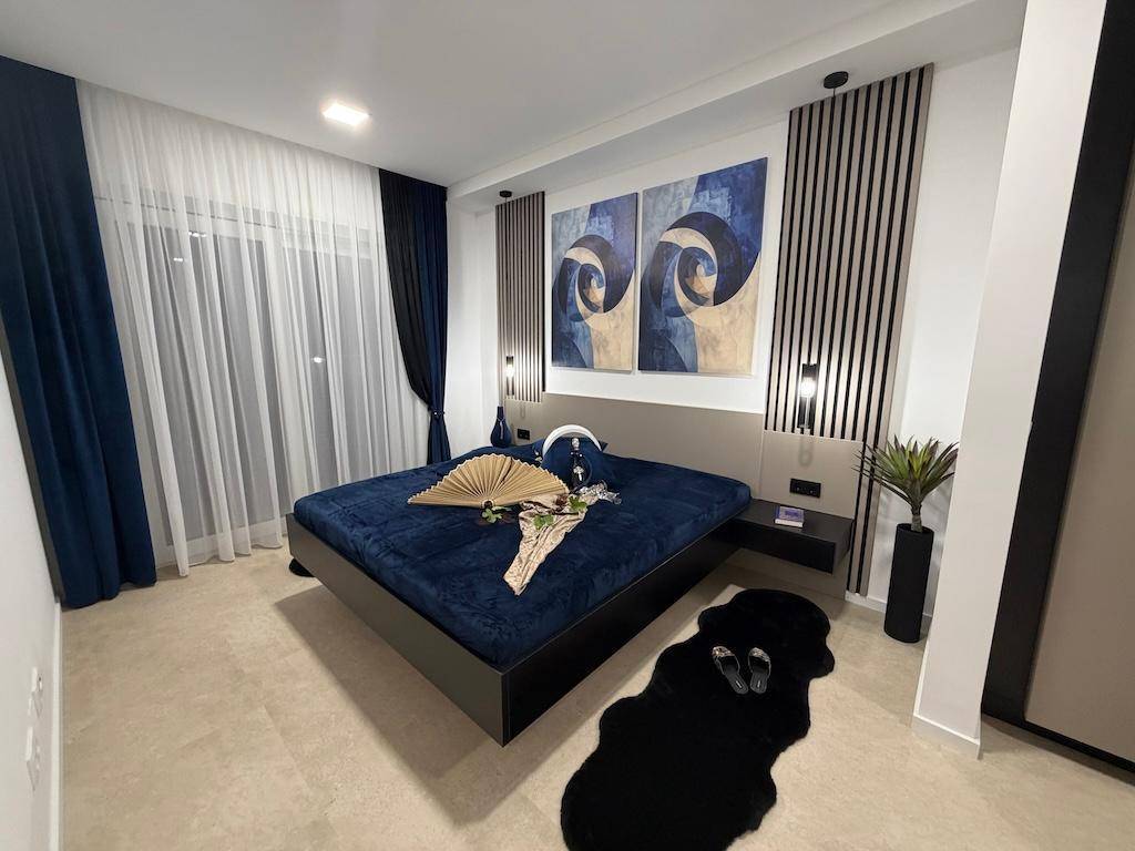 Helles Schlafzimmer mit großem Bett, blauer Bettwäsche und stilvollen Wandbildern.