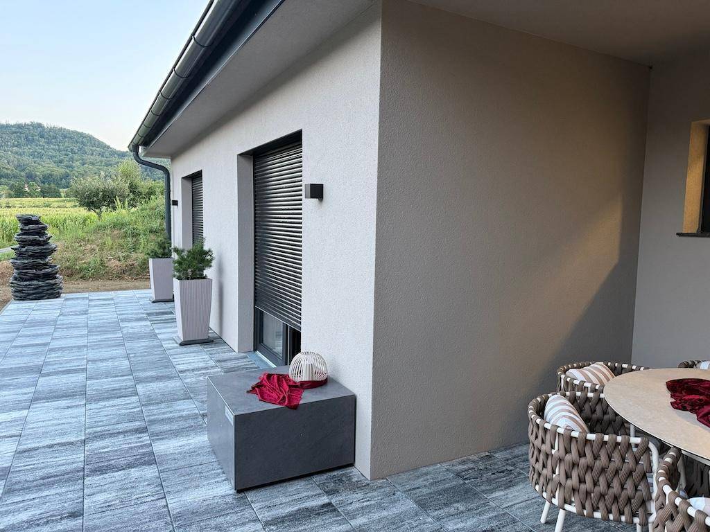Seitlicher Blick auf die moderne Terrasse mit Fliesenboden und Blick auf die grüne Landschaft.