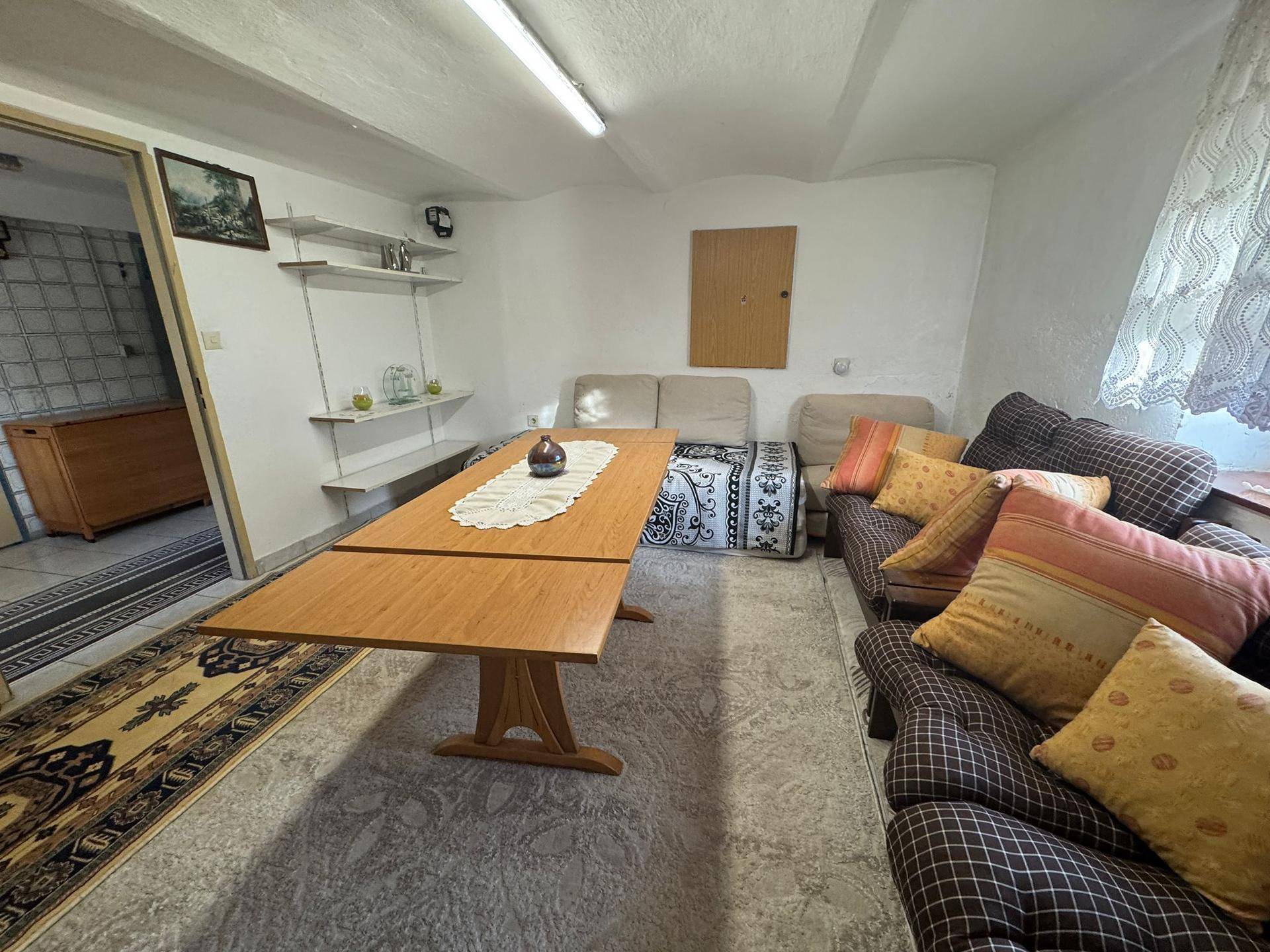 Geräumiger Kellerraum mit Sitzgelegenheiten, einem ausziehbaren Tisch und Teppichen.