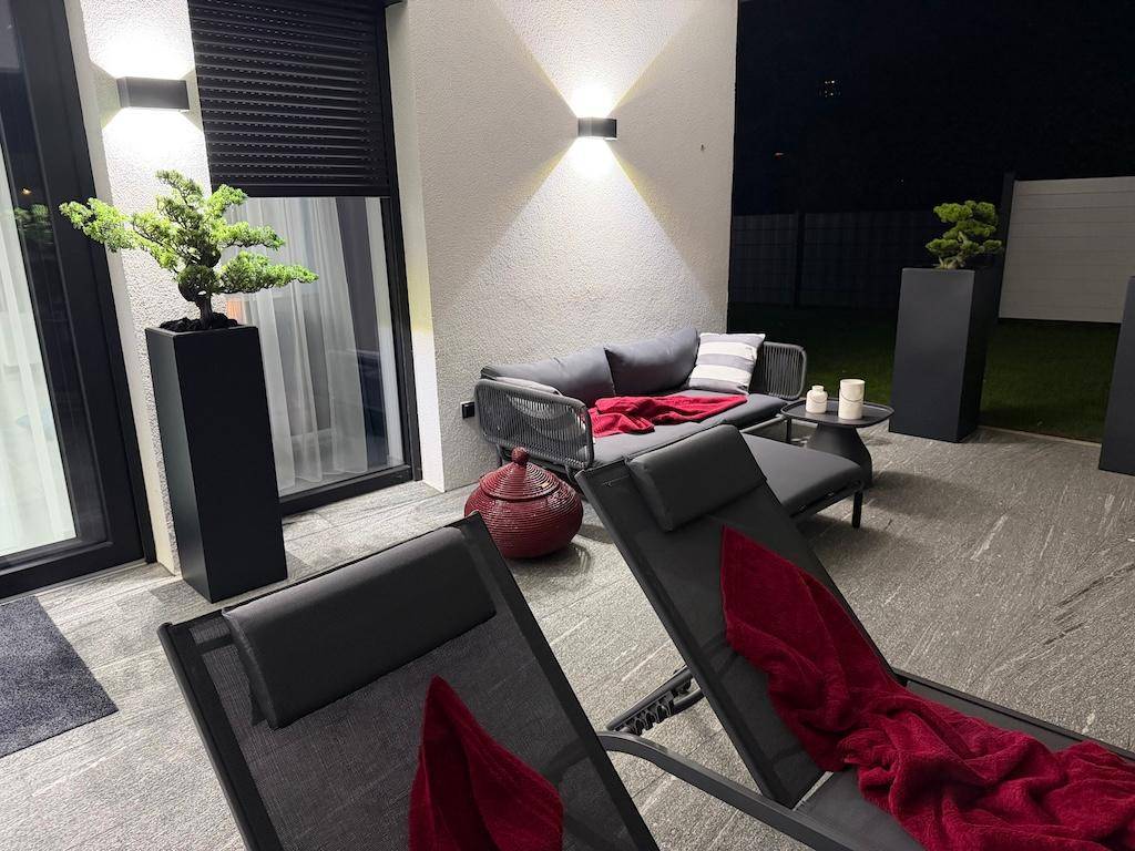 Gemütlicher Lounge-Bereich auf der Terrasse bei Nacht, mit bequemen Möbeln und stimmungsvoller Beleuchtung.