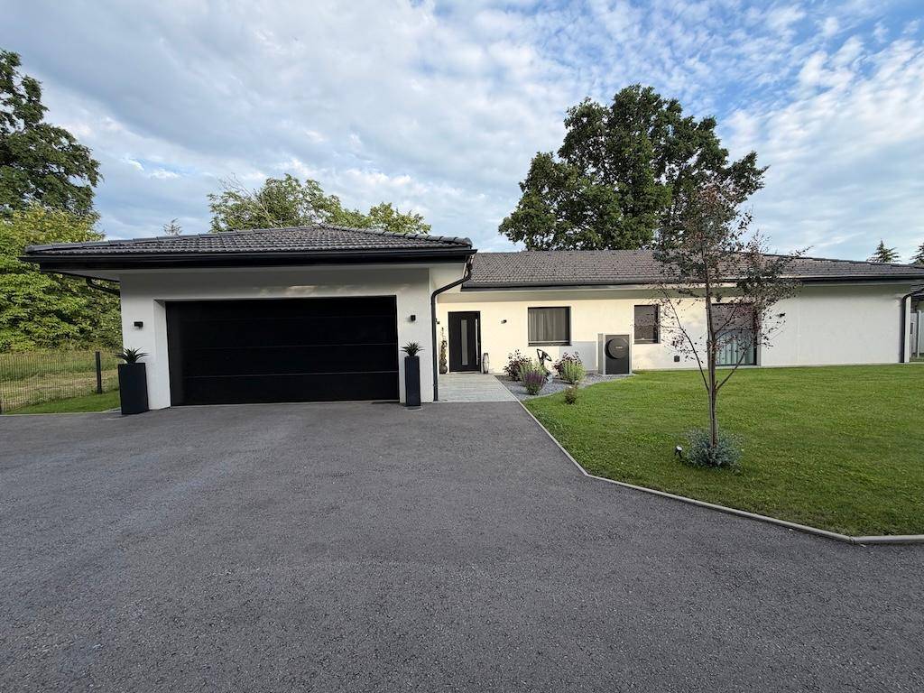 Vorderansicht eines modernen Einfamilienhauses mit integrierter Garage und gepflegtem Vorgarten.