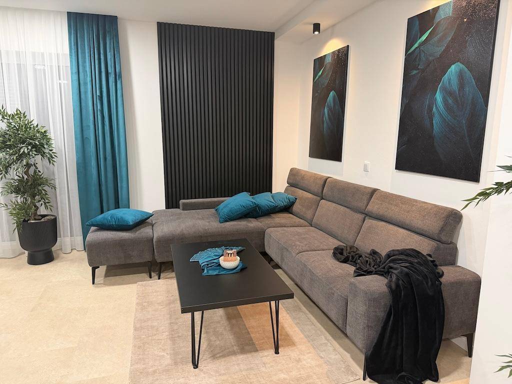 Gemütliches Wohnzimmer mit einem großen L-förmigen Sofa, Couchtisch und blauen Akzenten.