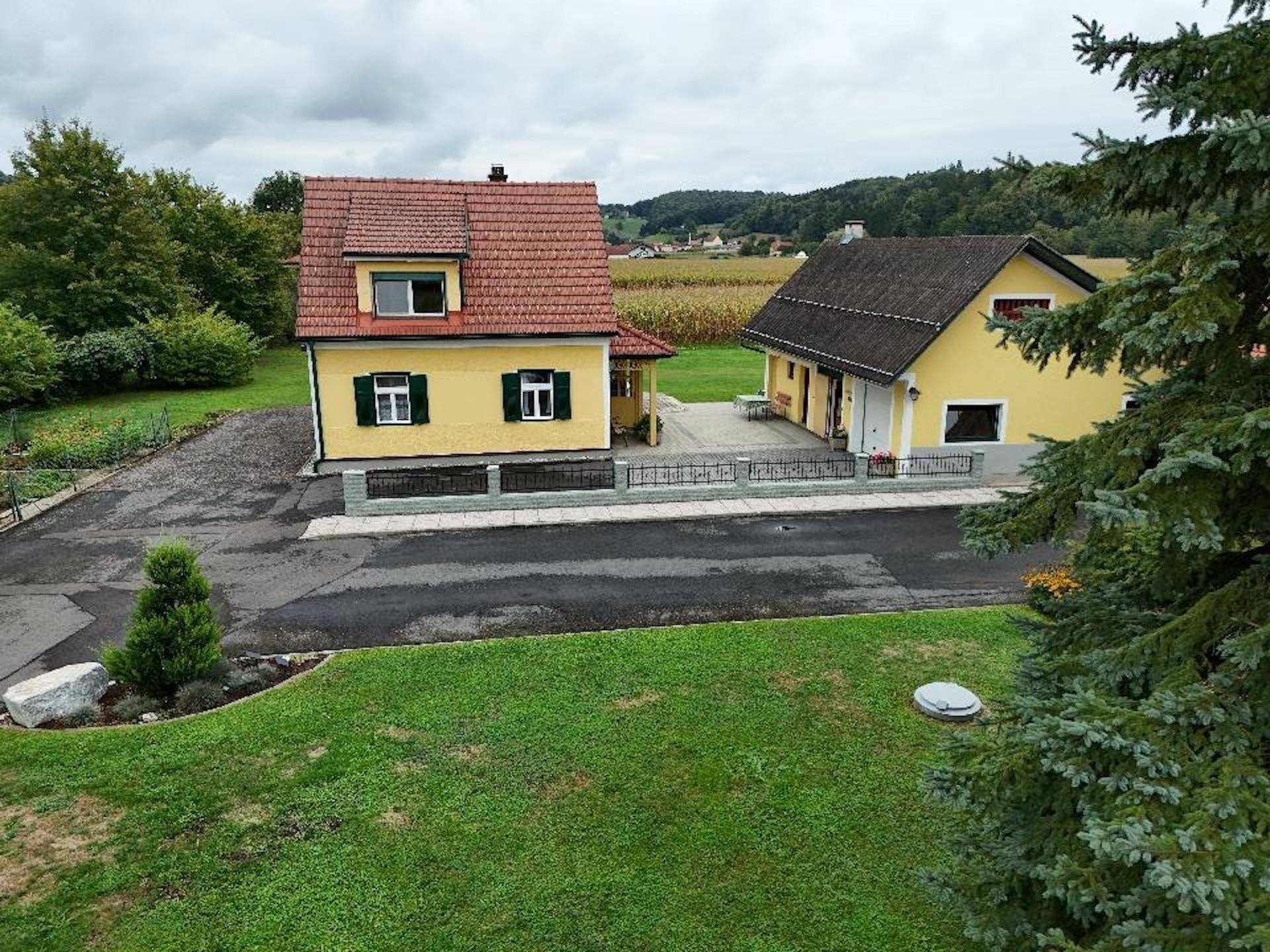 Weitläufige Luftaufnahme des Anwesens mit zwei Gebäuden, großem Rasen und ländlicher Umgebung.