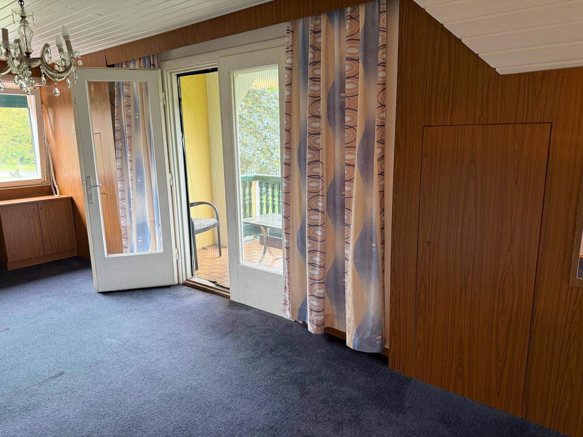 Geräumiges Zimmer mit Teppichboden und Zugang zu einem Balkon, der einen Ausblick ins Grüne bietet.