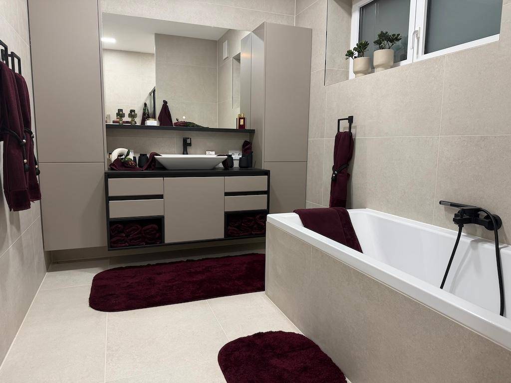 Modernes Badezimmer mit Badewanne, großem Waschtisch und hellen Fliesen.