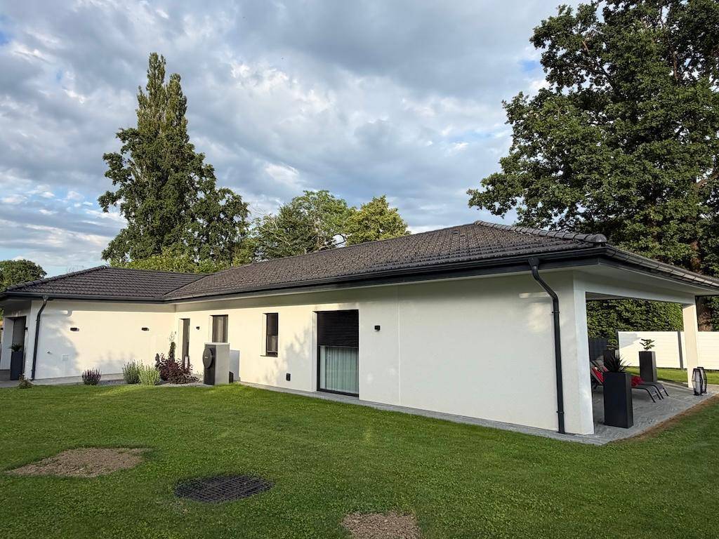 Seitenansicht des modernen Einfamilienhauses mit weißer Fassade und großem Rasenbereich.