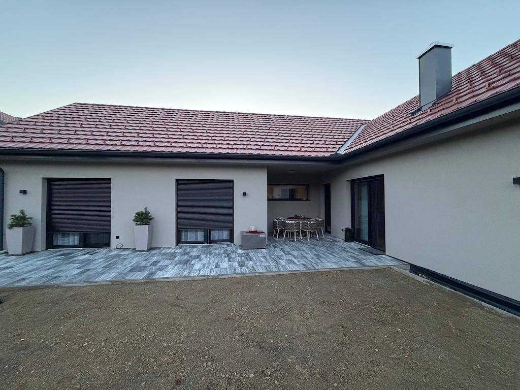 Weitläufige Terrasse mit grauen Fliesen und Blick auf den Gartenbereich des Neubaus.