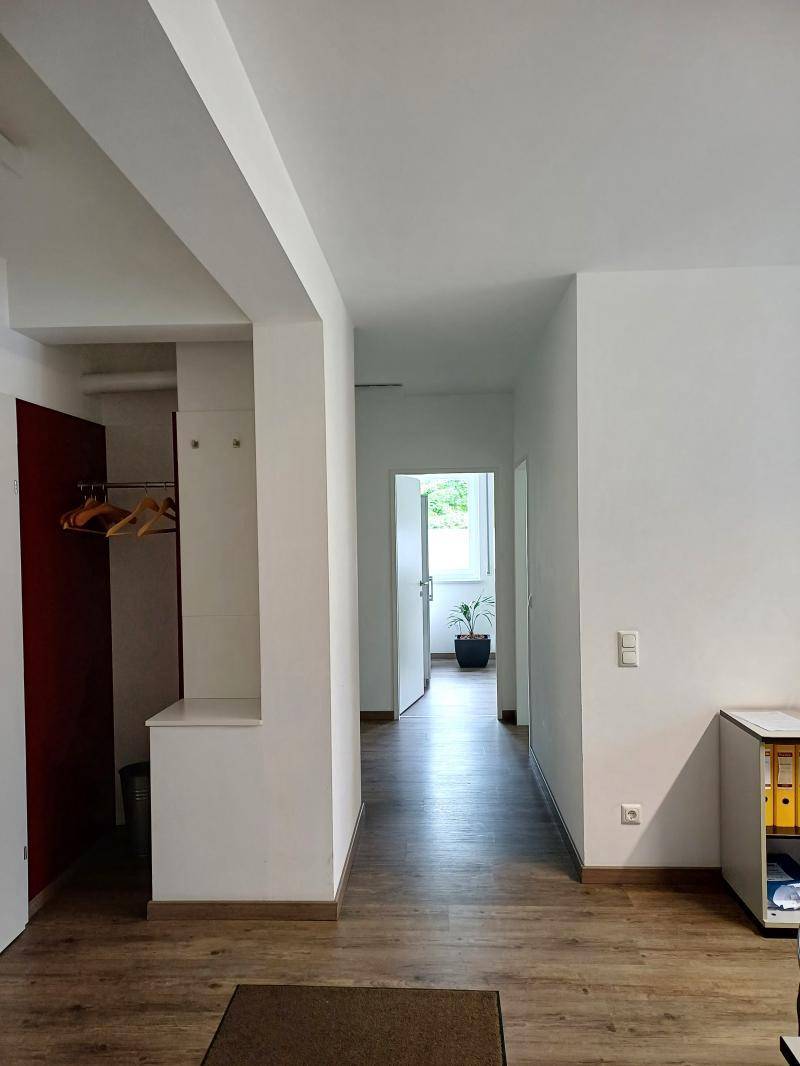 Heller Flur mit Garderobenbereich und Blick durch eine offene Tür in einen weiteren Raum.