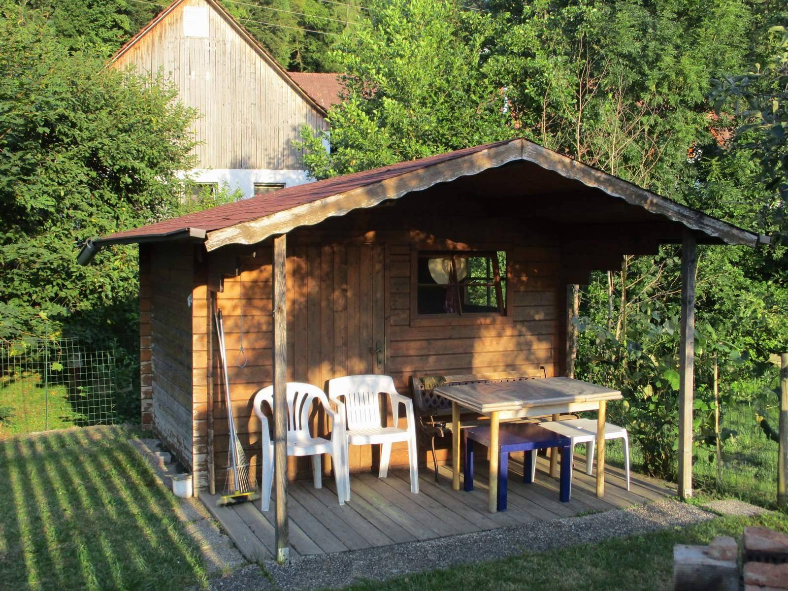 Gemütlicher Gartenpavillon mit Sitzgelegenheiten und Holztisch im Grünen.