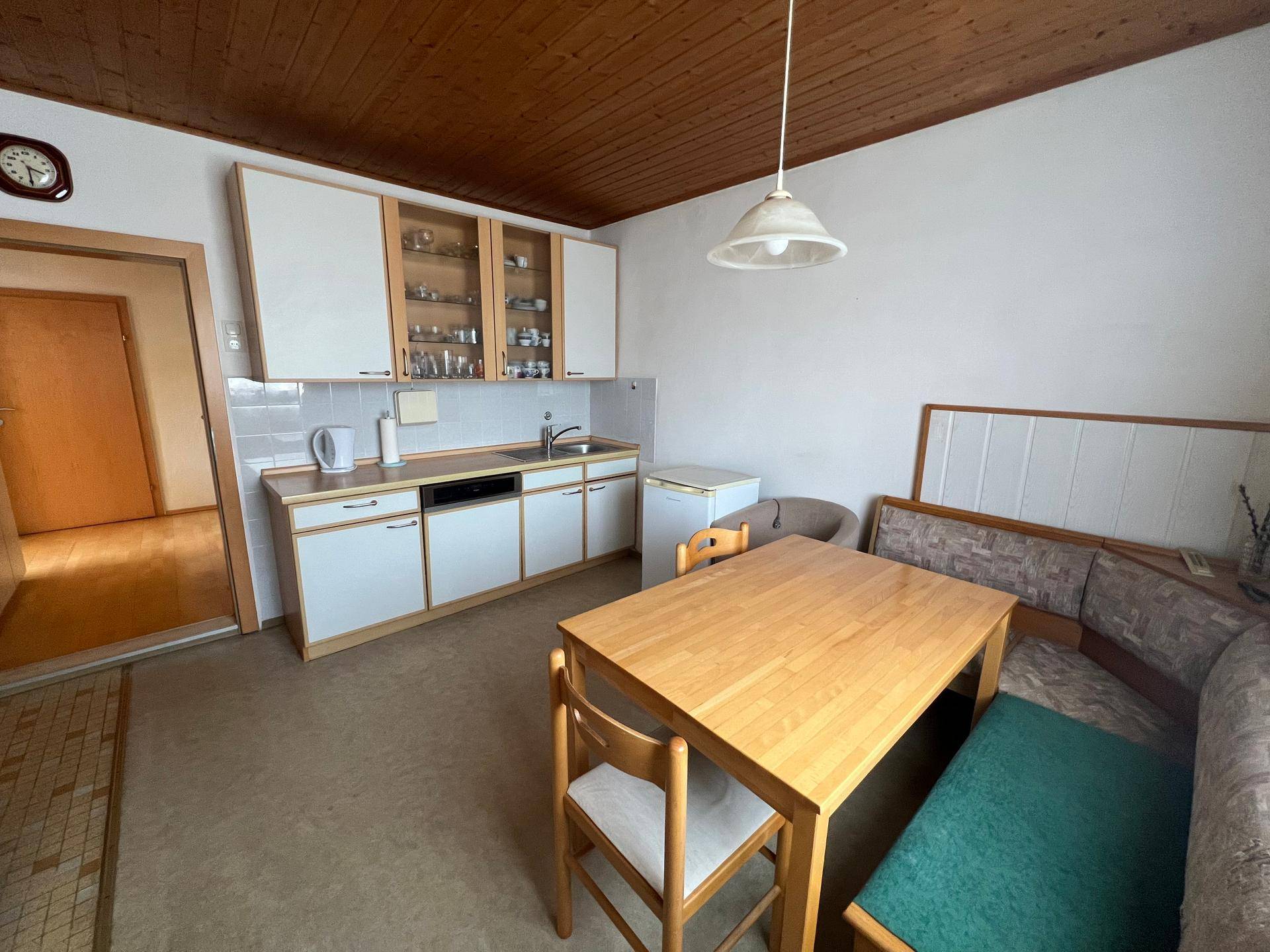 Gemütliche Wohnküche mit Eckbank, Holzdecke und funktionaler Küchenzeile.