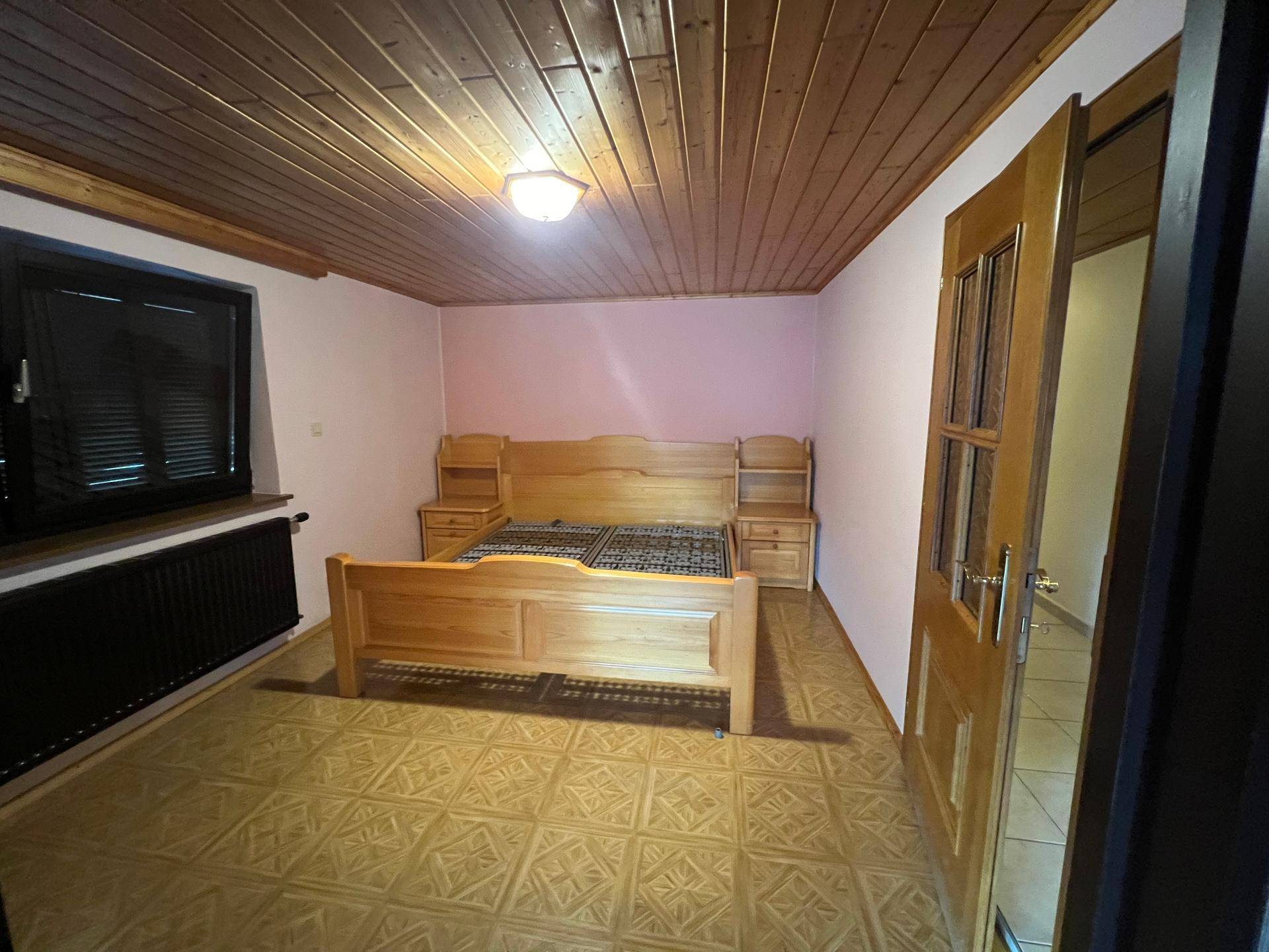 Schlafzimmer mit Holzbett, passenden Nachttischen und einer Holzdecke im traditionellen Stil.