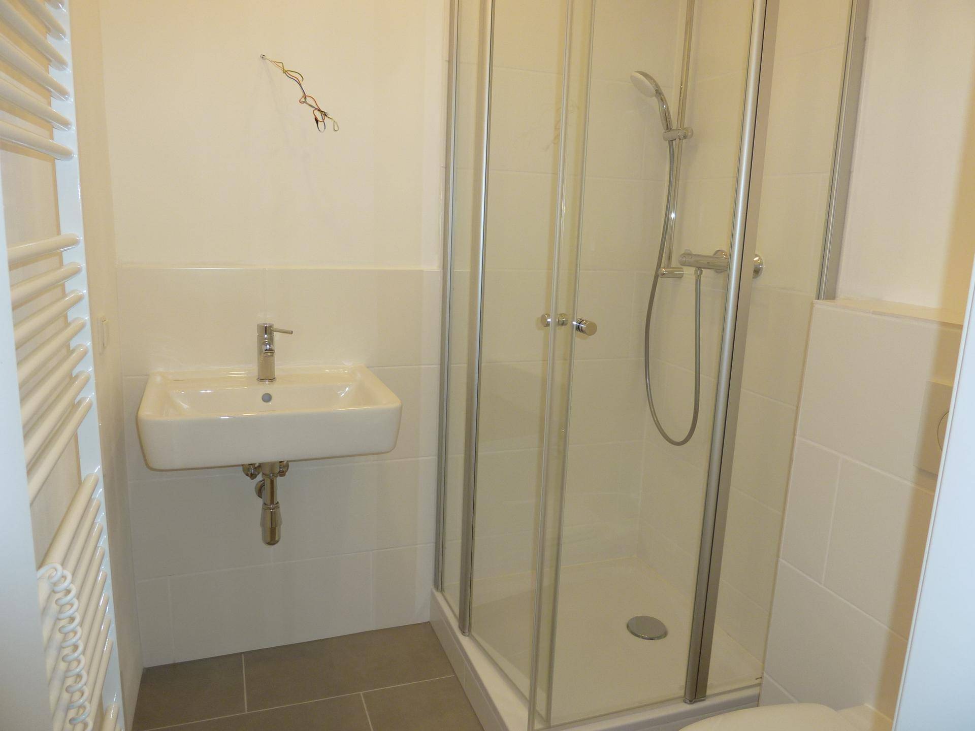 Modernes Badezimmer mit Duschkabine, Waschbecken und beheiztem Handtuchhalter.