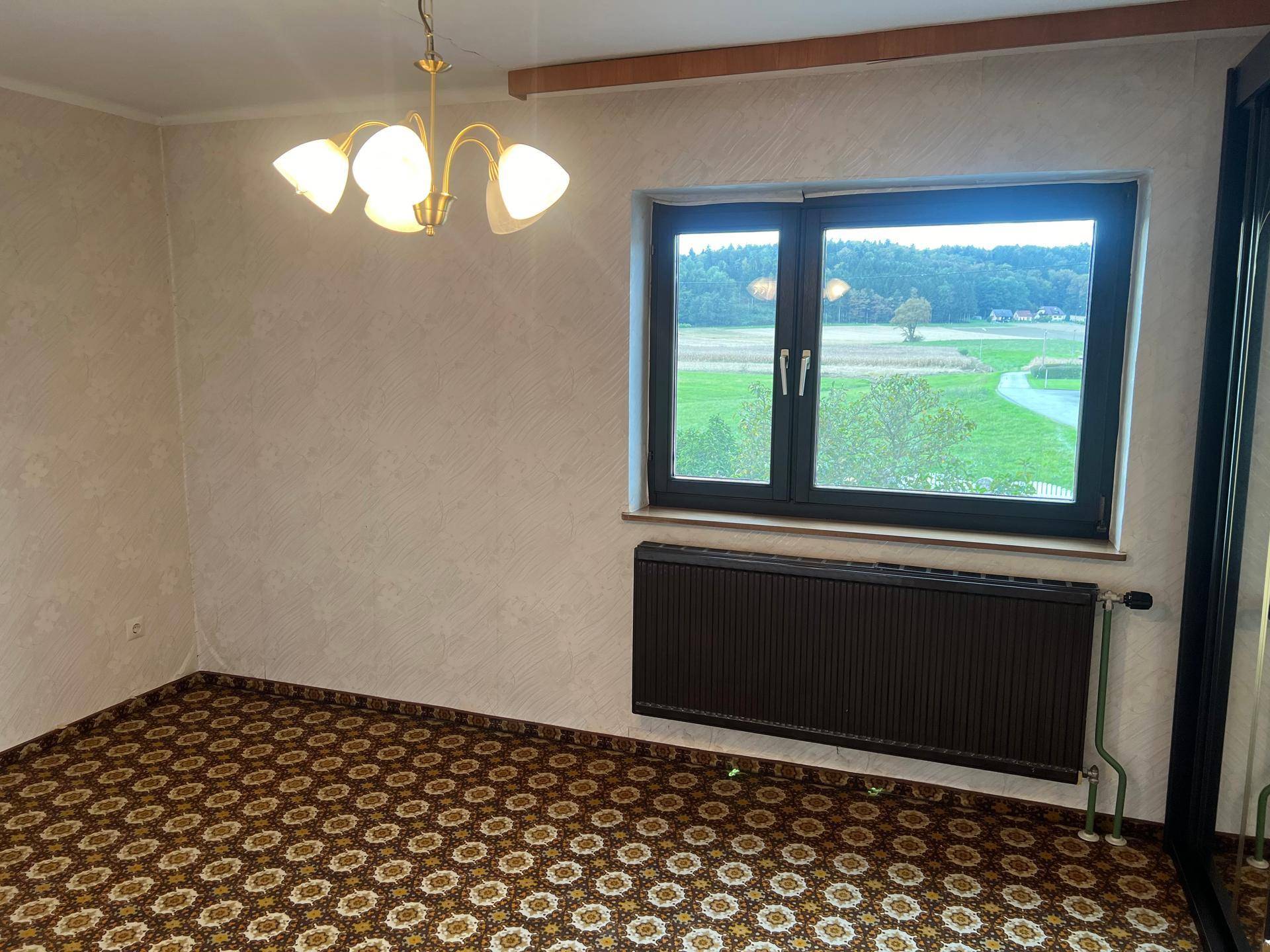 Helles Schlafzimmer mit gemustertem Teppichboden und weitem Blick auf die grüne Landschaft.