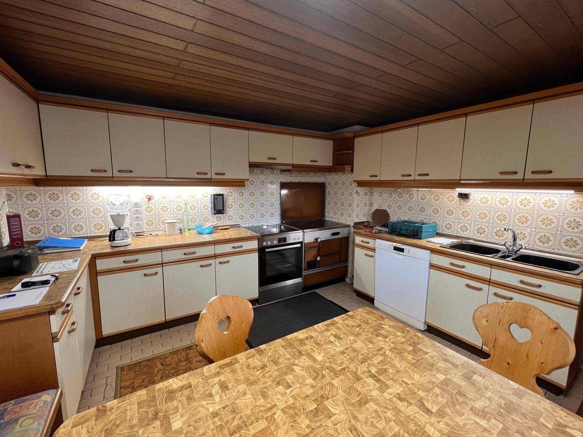 Gemütliche Küche im Landhausstil mit Holzdecke, integrierten Geräten und einem großen Esstisch.
