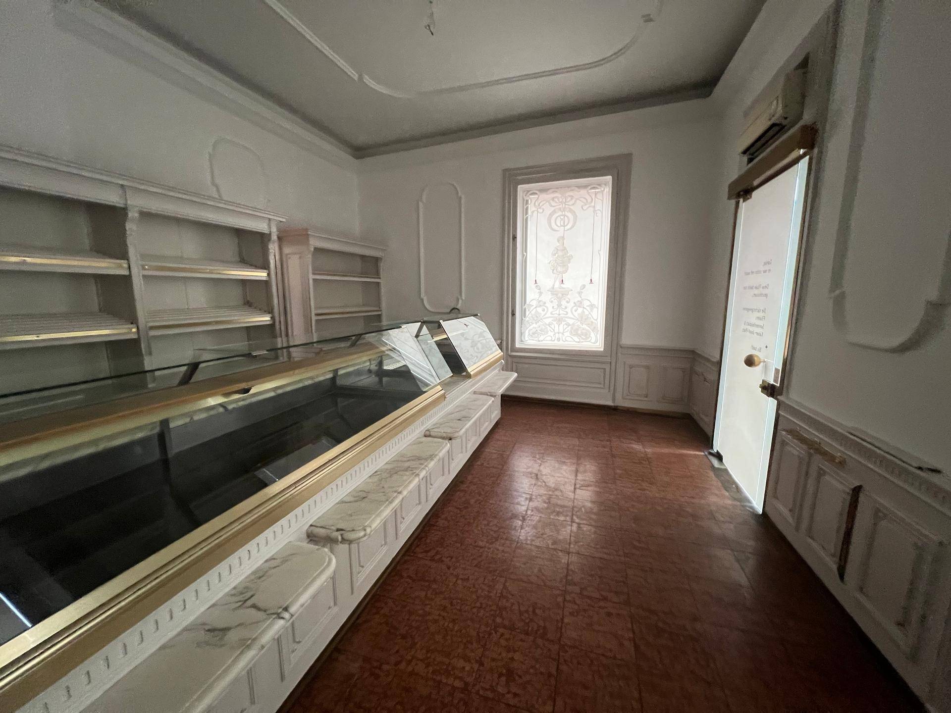 Historischer Ladenraum mit Vitrinen, Regalen, hohen Decken und dekorativen Wandpaneelen.