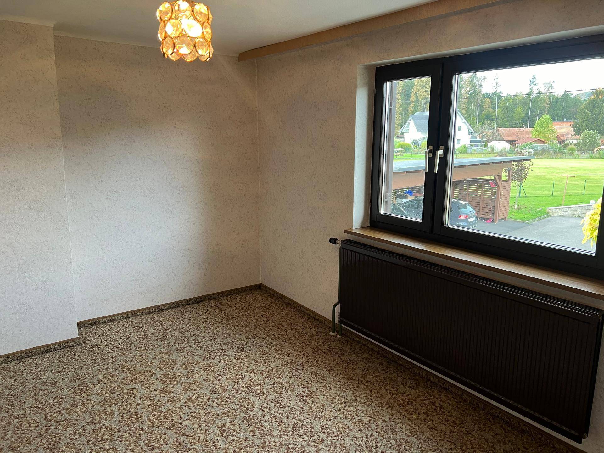 Schlafzimmer mit gemustertem Teppichboden, großem Fenster und Blick auf die umliegende Landschaft.