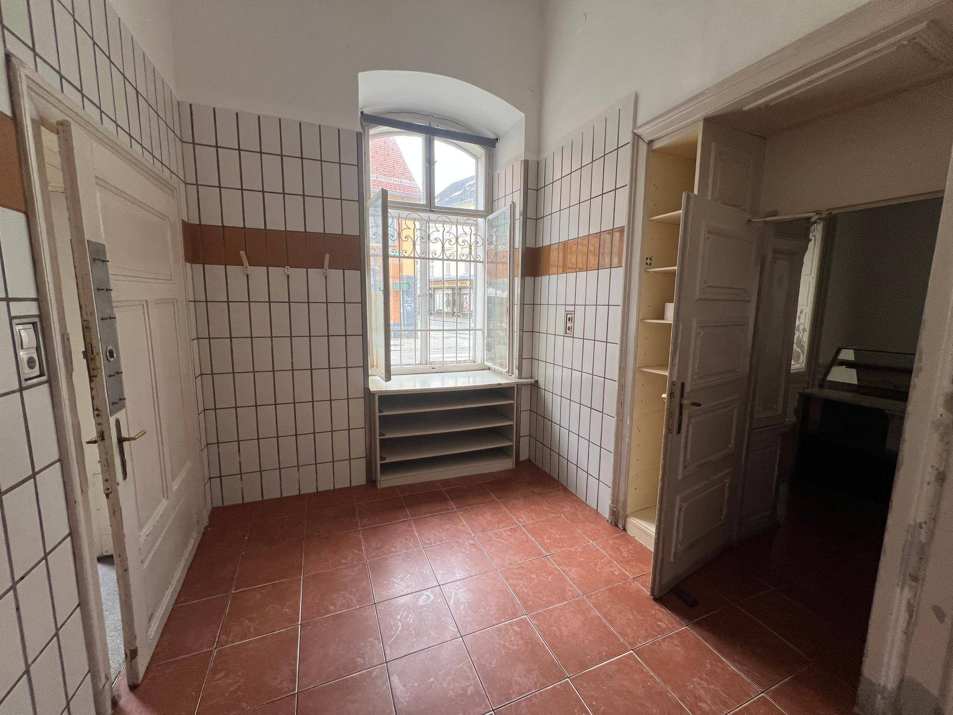 Gefliester Raum mit Fenster, Spülbecken und einfachen Schränken, ideal als Vorbereitungsbereich.