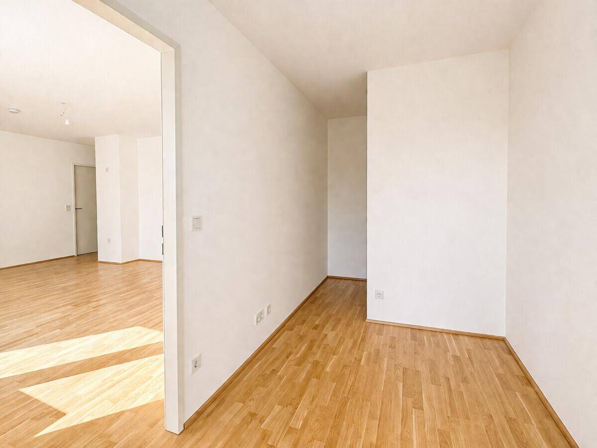 Heller Flur mit Parkettboden, der zu weiteren Zimmern führt und viel Tageslicht empfängt.