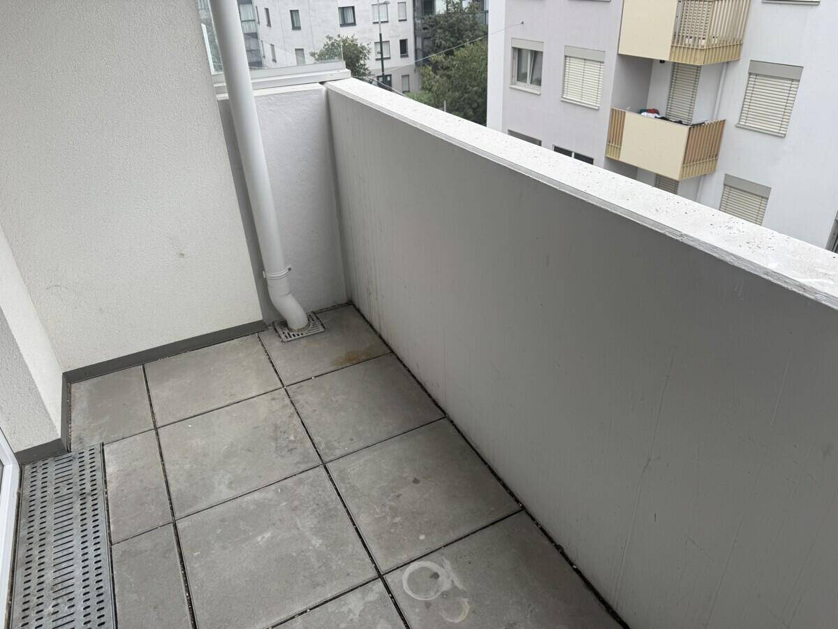 Kleiner Balkon mit Fliesenboden und Blick auf die umliegenden Gebäude.
