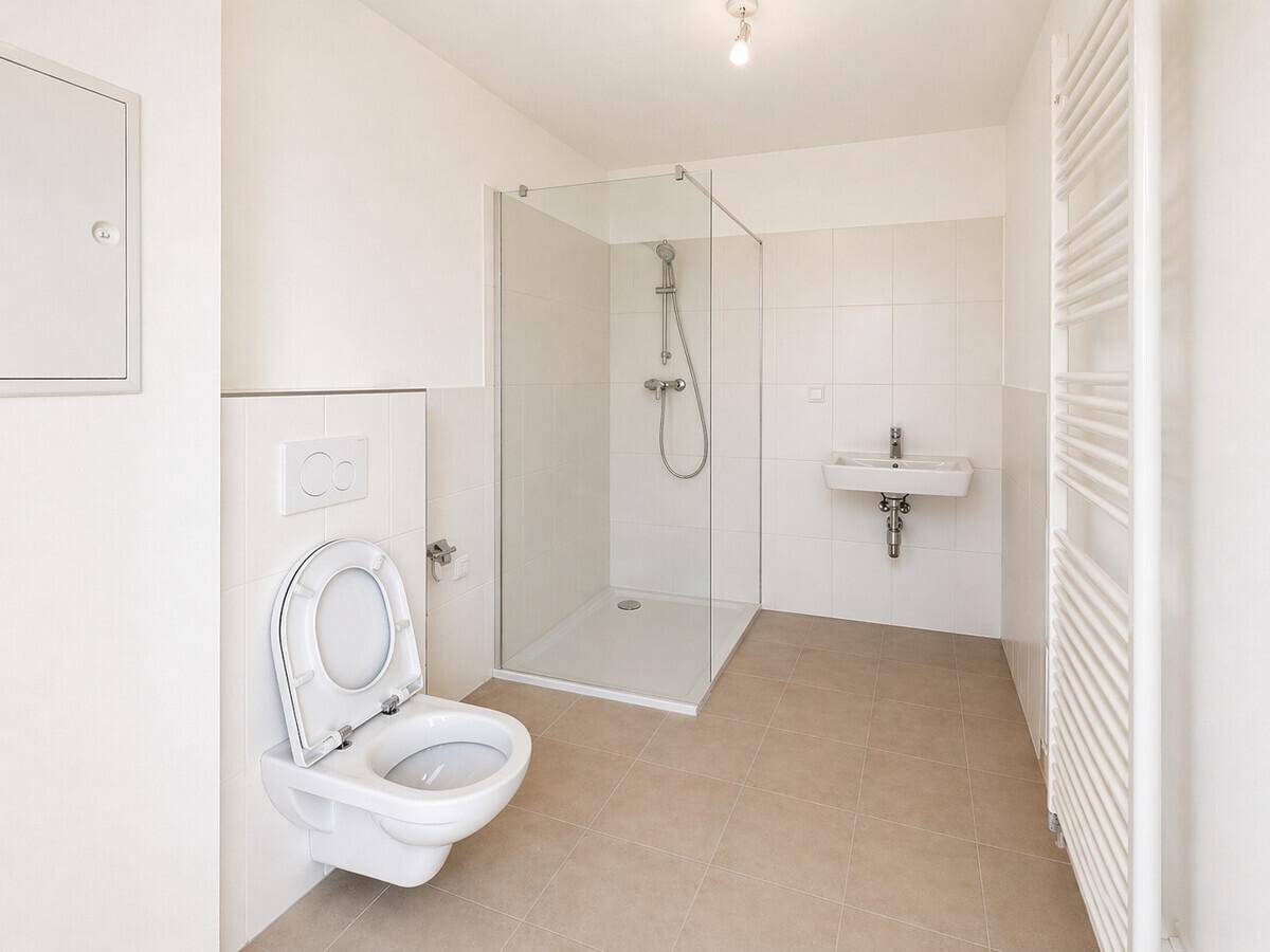 Modernes Badezimmer mit wandhängendem WC, ebenerdiger Dusche und Handtuchheizkörper.