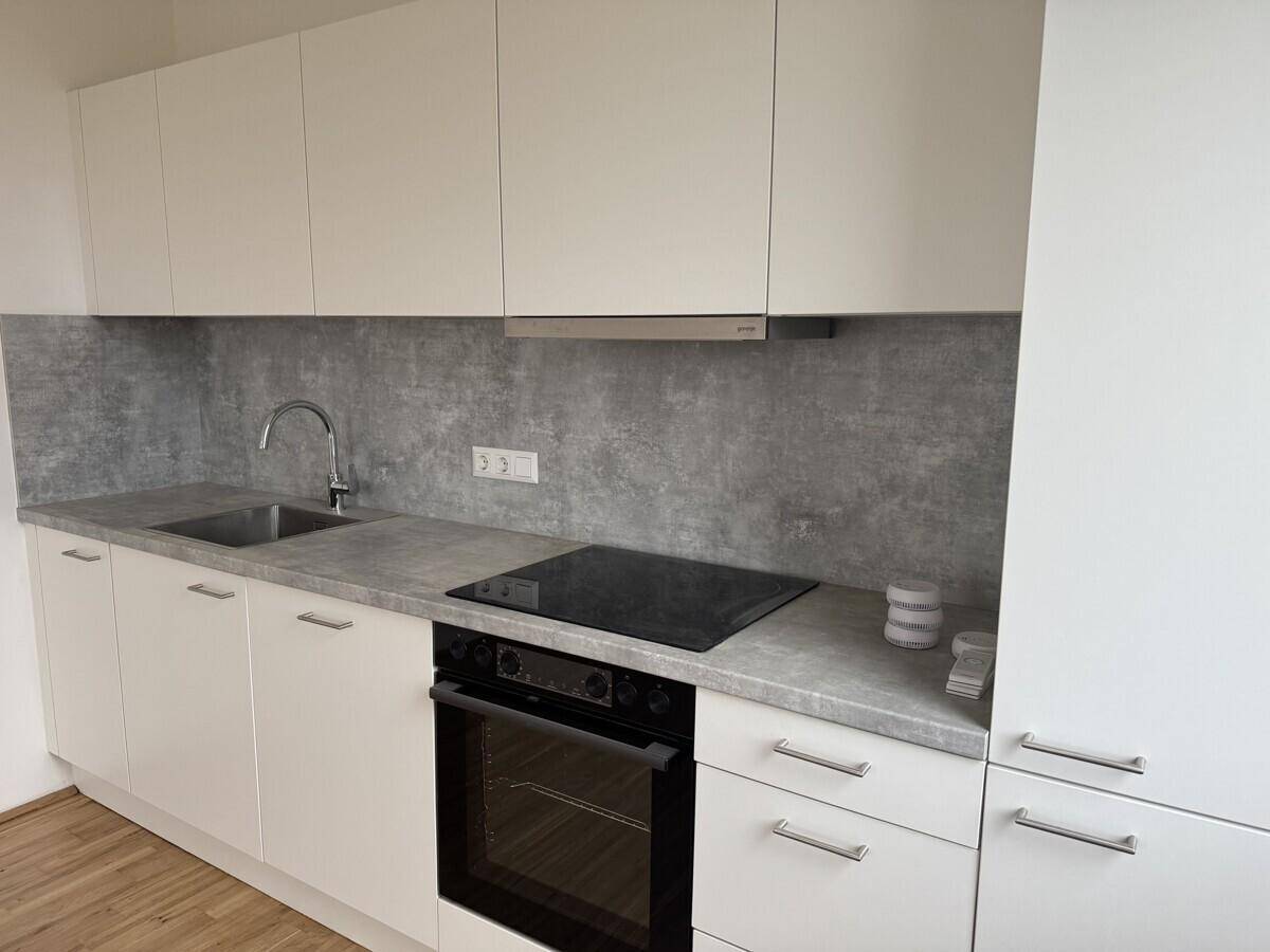 Moderne Einbauküche mit weißen Fronten, Induktionskochfeld und Backofen.